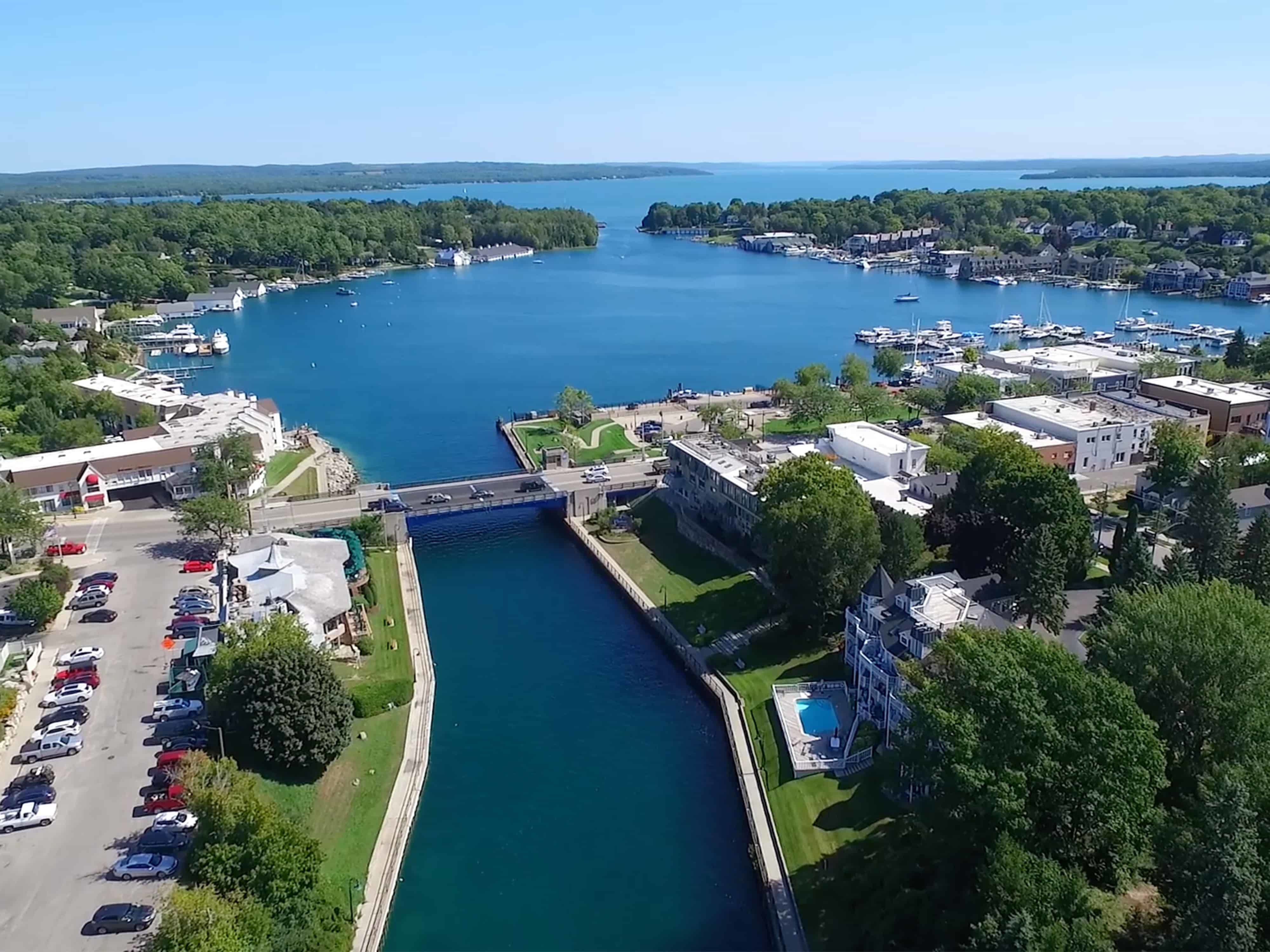 A view of Lake Charlevoix in Charlevoix, Michigan, with boats on the water and lush greenery around.