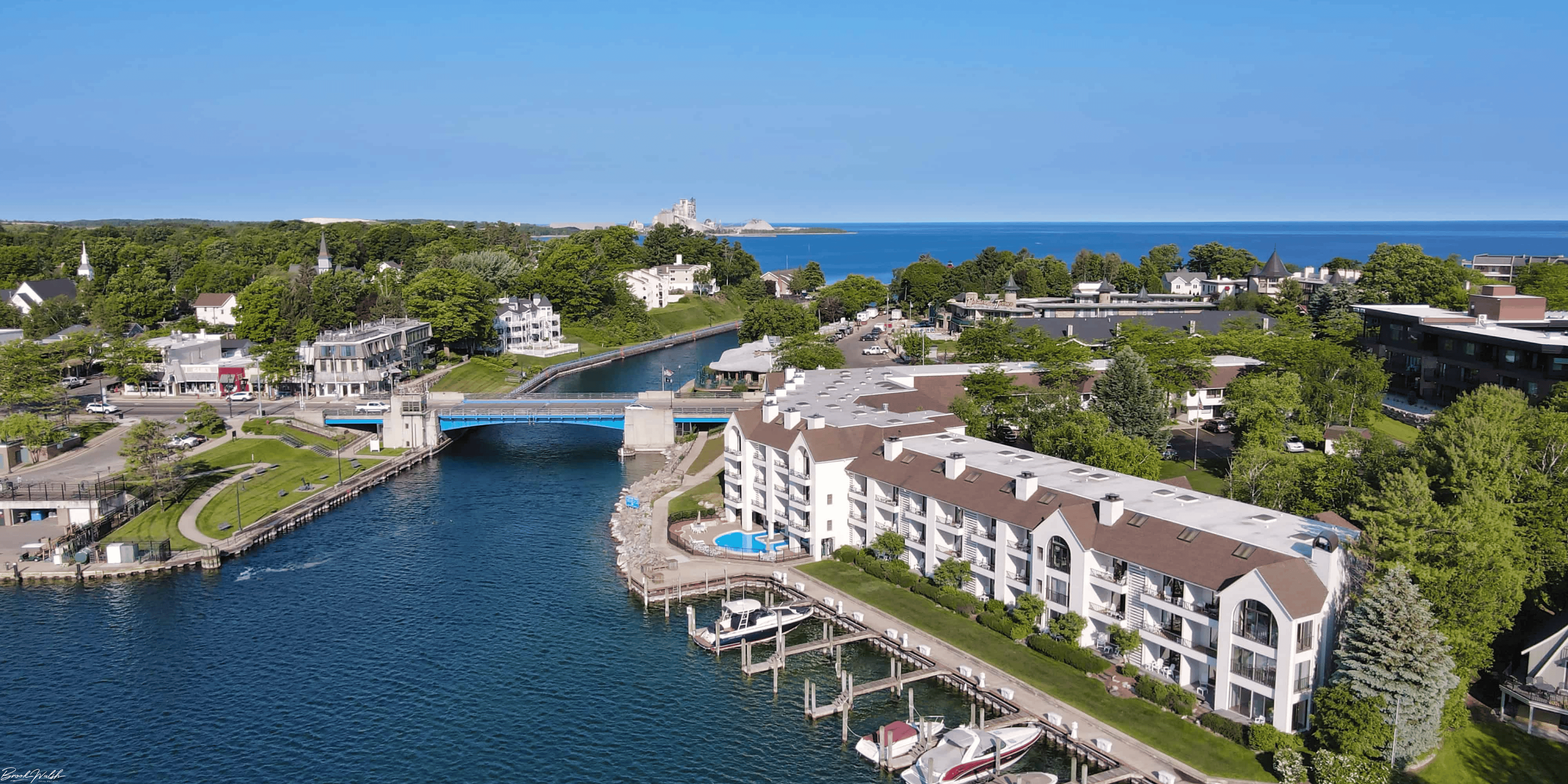 Aerial view of luxury waterfront hotels along Lake Charlevoix surrounded by lush greenery and clear blue water.