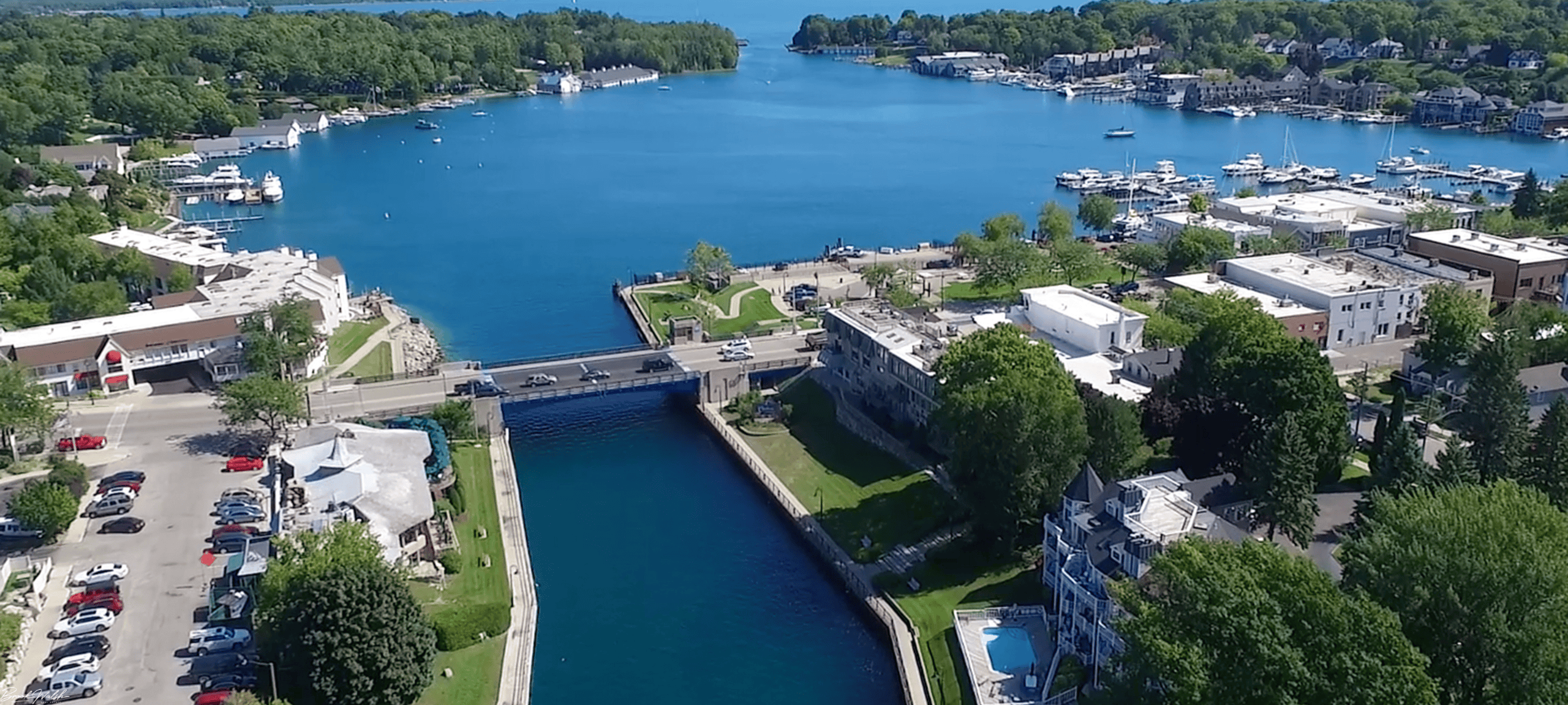Downtown Charlevoix waterfront with boats, shops, and scenic lake views during a sunny day