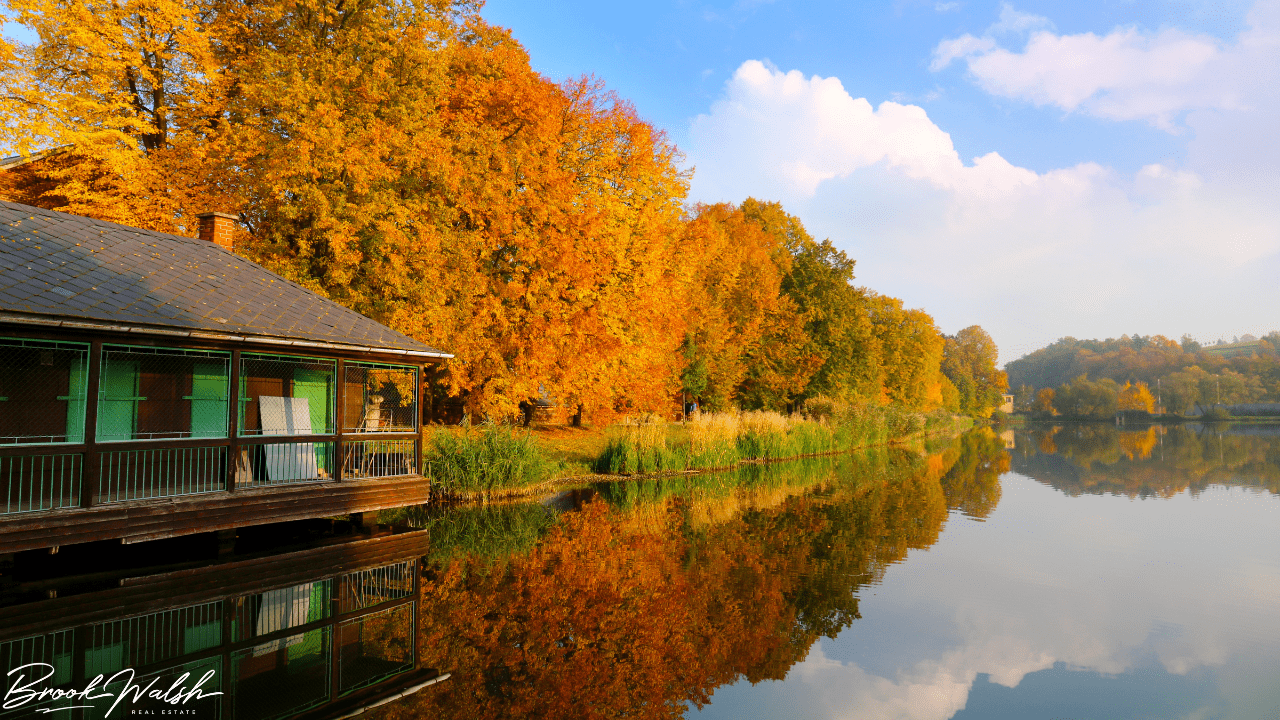 A serene lake view with a small cottage on the shore. 